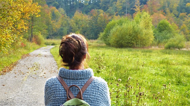Mujer de espaldas mirando apaciblemente un campo verde y arbolado