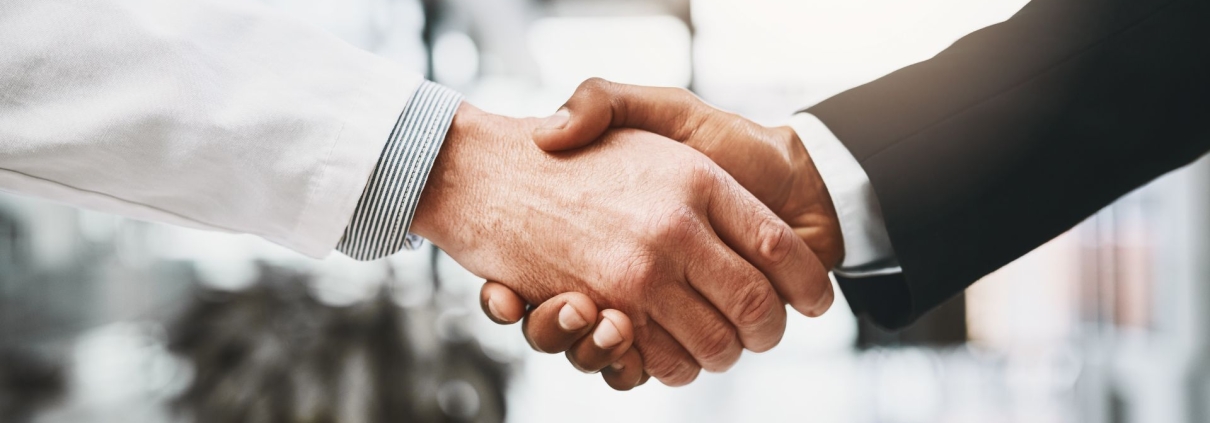 Primer plano de un apretón de manos entre dos profesionales en un entorno corporativo, simbolizando la confianza, el compromiso y la formalización de acuerdos. La imagen representa la importancia de establecer acuerdos claros en el liderazgo conversacional para fortalecer la responsabilidad y el desempeño dentro de los equipos.
